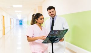 Hispanic doctor and nurse discussing over xray while standing together in corridor at hospital